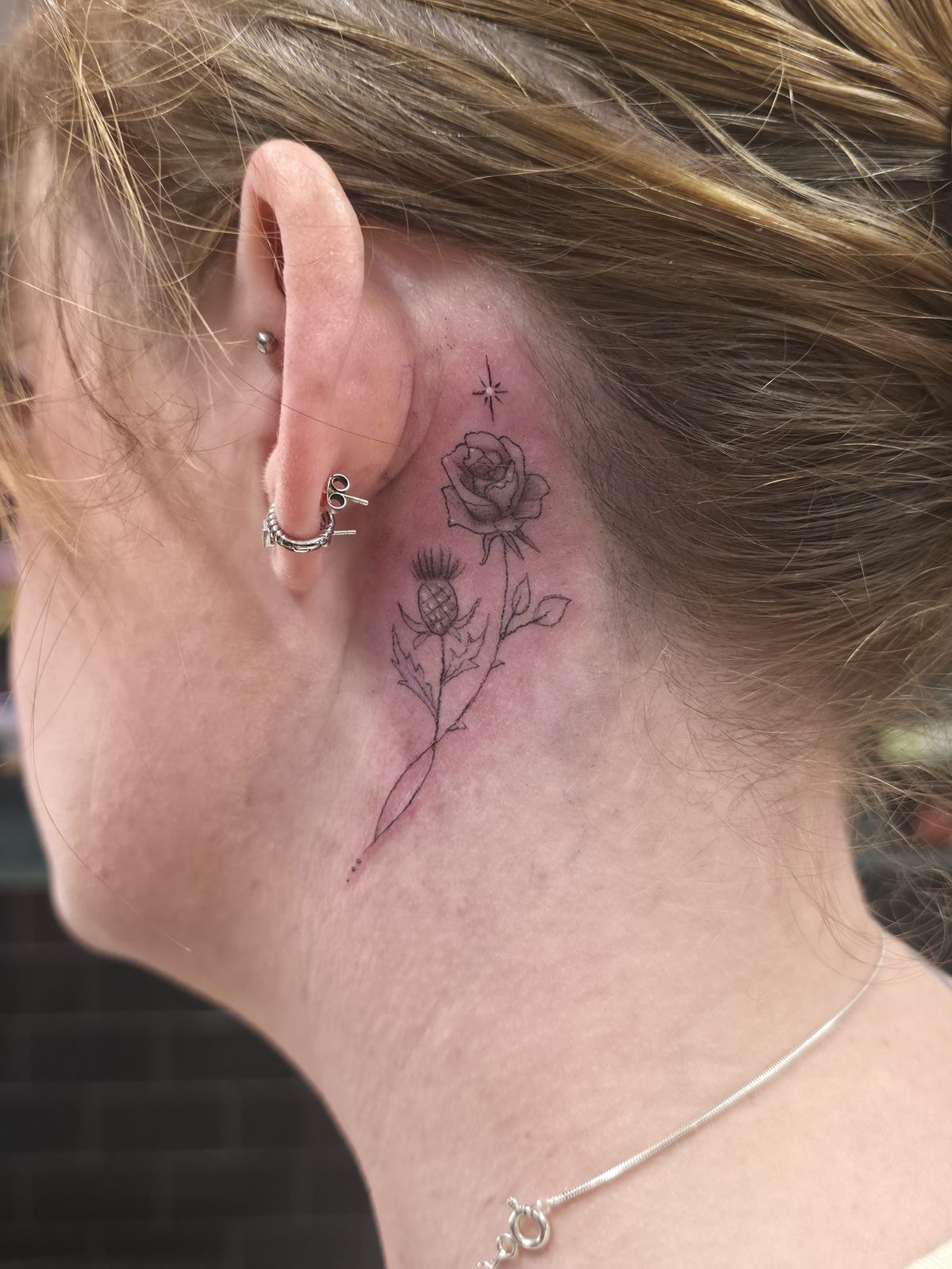 ROSE + THISTLE tattoo — fine line, behind ear — by Kayleigh Chaos, tattoo artist in Perth, Scotland