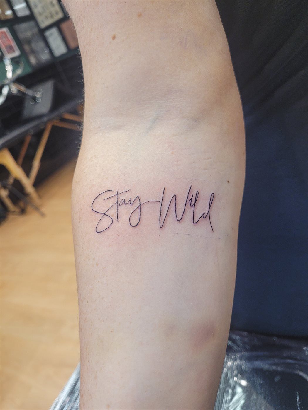 STAY WILD tattoo — script, upper arm — by Kayleigh Chaos, tattoo artist in Perth, Scotland