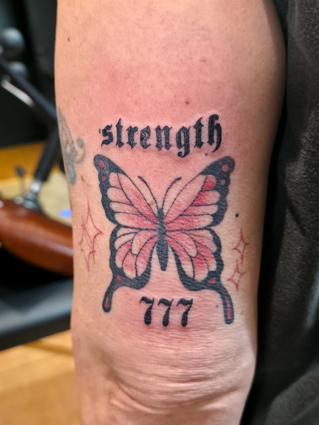 STRENGTH 777 tattoo — script, upper arm — by Kayleigh Chaos, tattoo artist in Perth, Scotland